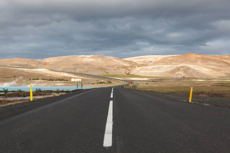 冰岛路与褐色山在地平线空的路在冰岛风景湖附近的郊区