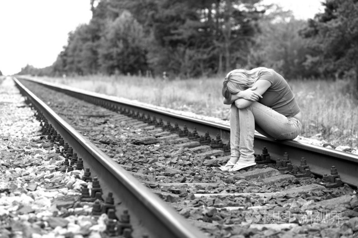 难过的女孩坐在铁轨上