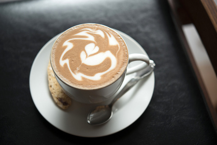 热摩卡拿铁艺术在黑色的桌子上照片