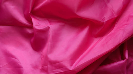 粉红色的合成衬里织物与褶皱。皱巴巴的床单或衣服背景