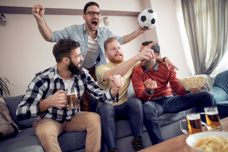 友谊, 体育和娱乐快乐的男性朋友与啤酒, 爆米花和薯条看体育在家里