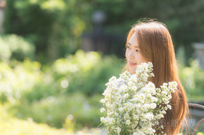 亚洲美丽女孩在草地上拿着花