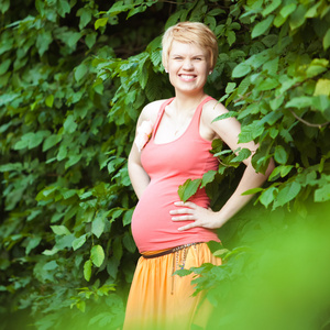 年轻的幸福的怀孕的女人的在自然中放松