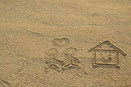 恩爱的情侣和心形图案画在沙滩上的房子