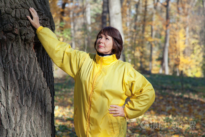老年妇女走在秋天的树林