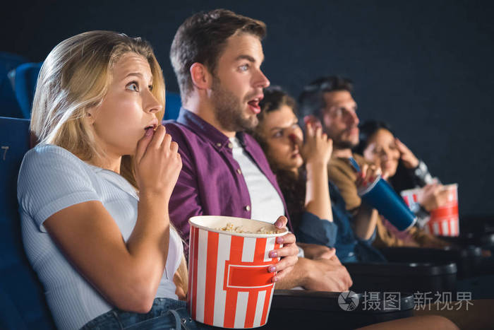 害怕多民族朋友与爆米花一起看电影在电影院
