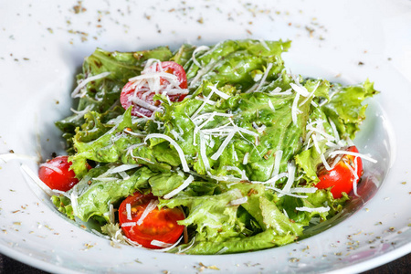 新鲜的沙拉与混合蔬菜, 樱桃西红柿, 帕尔马干酪在木质背景。健康食品。餐桌上的配料