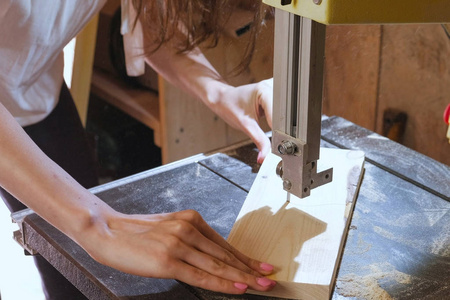 Craftswoman 正在用锯切割木材工件。特写手