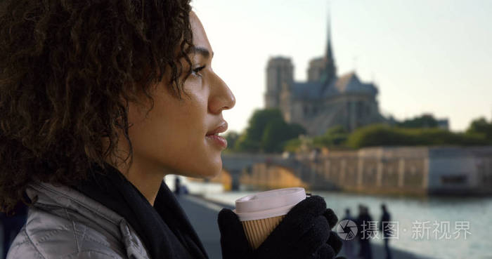 关闭可爱的黑人女性喝咖啡, 并环顾巴黎圣母院附近