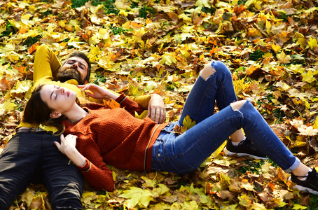 相爱的情侣躺在公园里干枯的落叶上