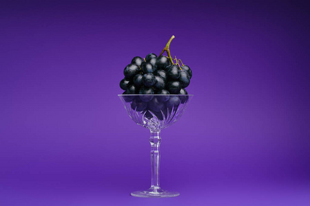 在紫罗兰色背景的玻璃新鲜成熟葡萄的特写镜头视图