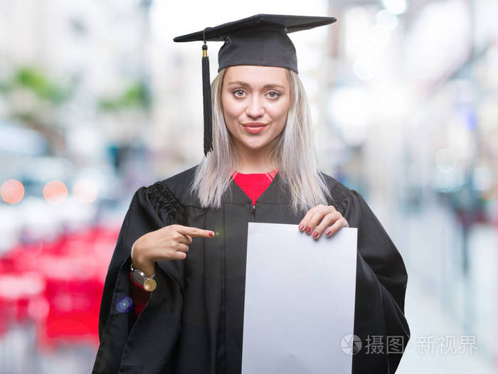 年轻的金发女子穿着研究生制服持有学位在孤立的背景非常高兴的手指与手和指头