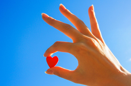 天空创造力在天空中的女人的手一颗红色的心照片
