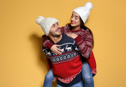 年轻夫妇在温暖的毛衣和针织帽子的颜色背景。圣诞庆典