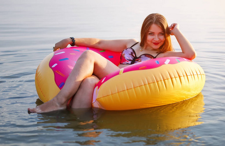 快乐的女孩在洒甜甜圈漂浮和微笑在海在夏天时间