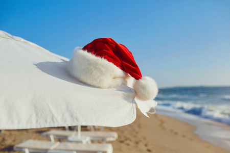 在海边海滩上的圣诞老人帽子。圣诞节假期 b