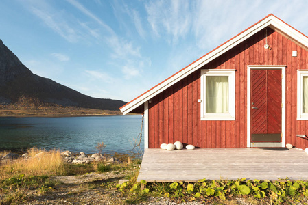 在一个阳光明媚的蓝天上俯瞰特罗姆瑟峡湾北极圈挪威和山顶的木制挪威海滨小屋