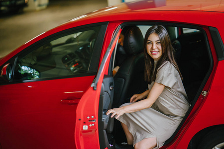 美丽的年轻亚洲妇女走出红色汽车