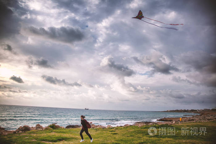 一个年轻女子在海边奔跑放飞风筝旅行和度假的概念生活的乐趣