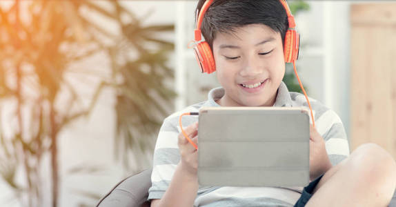 亚洲青少年在家里玩平板电脑面带微笑