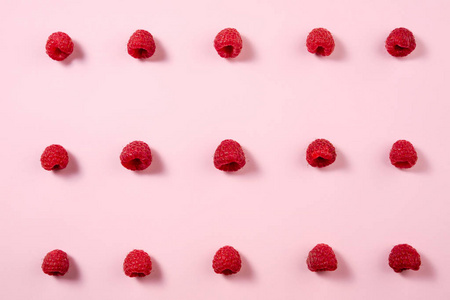 淡粉色背景下的覆盆子图案。平躺, 顶部视图。与浆果的食物背景。创意极简主义