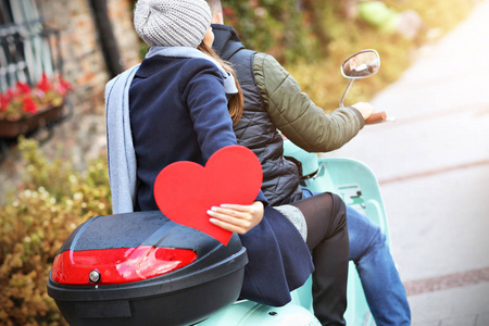 秋天的心美丽的年轻夫妇抱着心脏, 而骑摩托车在城市在秋天照片