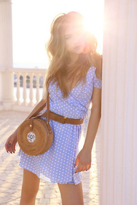 时尚的户外照片美丽的年轻女子与金发在优雅的夏季礼服和稻草袋步行 aroung 城市