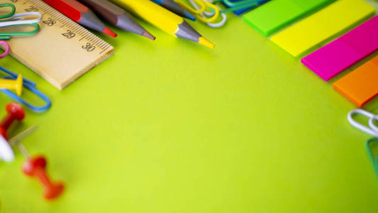 学校用品在绿色背景与拷贝空间。办公室桌上的钢笔铅笔剪刀尺子回形针和记号笔