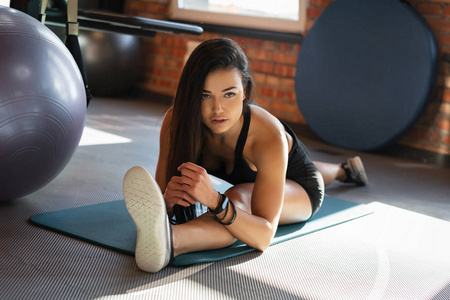 灵活的运动女孩做伸展在健身房的分裂