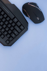 黑色鼠标和键盘上的蓝色背景, 顶部视图。工作场所, 鼠标和键盘平躺。计算机设备