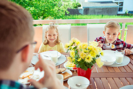快乐的年轻家庭有乐趣在早餐大 terrasse 在家中