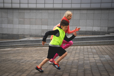 运动的年轻女子和男孩正在城市景观的背景下运行。家庭体育