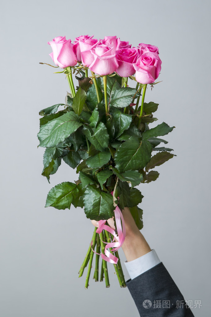 粉红色的玫瑰花在男性手中的花束
