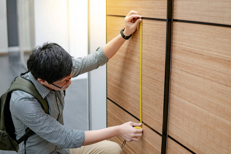 室内设计理念年轻的亚洲男人用卷尺测量现代橱柜,走在壁橱陈列室里.