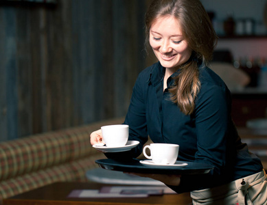 服务员拿着托盘的咖啡杯在咖啡馆里的肖像