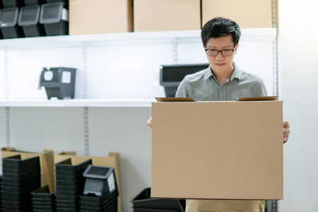 年轻的亚洲人拿着纸板箱选择买什么。仓储购物理念