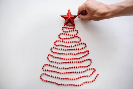 一个人创造一个创造性的圣诞或新年树由珠子制成的简约风格和装饰与明星