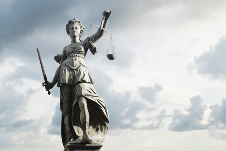 Justitia 的象征正义在背景面前与天空和云彩。正义与法律概念