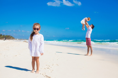 年轻的父亲和他可爱的女儿，在白色的沙滩上尽情的