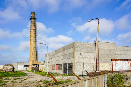 废弃的工业建筑与一个高砖烟囱对蓝天, 栅栏带刺的电线
