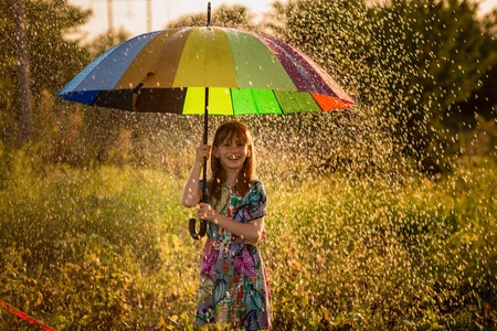 快乐的孩子女孩漫步与多彩多姿的雨伞下夏季雨