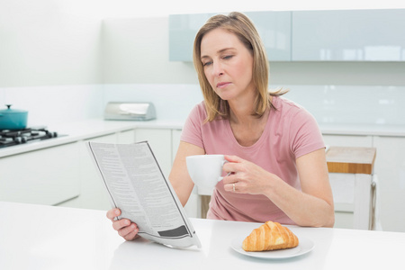 集中的女人，在厨房里喝咖啡时被读报纸