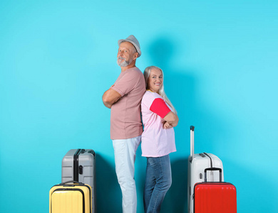 带着彩色背景行李箱的高级夫妇。度假旅行