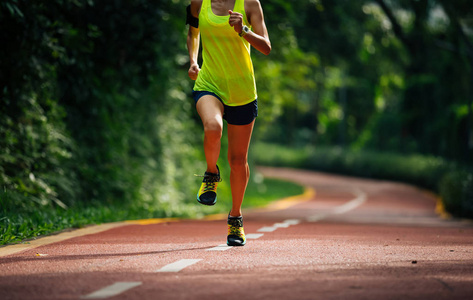 健康妇女赛跑者奔跑在早晨公园路