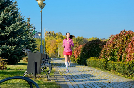 公园晨跑风景在秋天公园,美丽的女孩跑慢跑在户外跑步的女人照片
