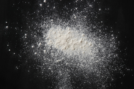 黑色带纹理的背景上的白色粉体爆炸照片