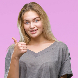 年轻的白种女人在孤立的背景做愉快的拇指手势与手。批准表达式看着相机显示成功