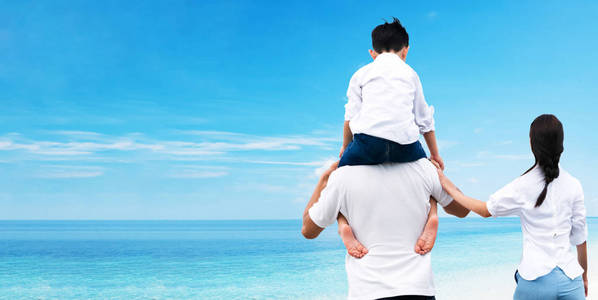 幸福家庭的母亲和父亲背着儿子在他的肩膀上度假