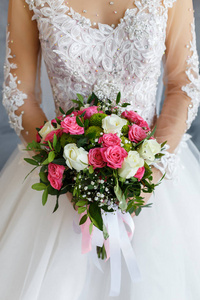 新娘穿着蕾丝礼服, 手持白色和粉色玫瑰的婚礼花束