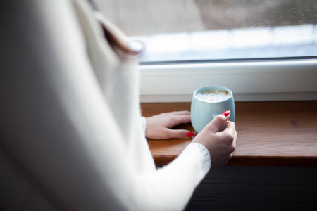 穿暖毛衣的女人拿着杯可可